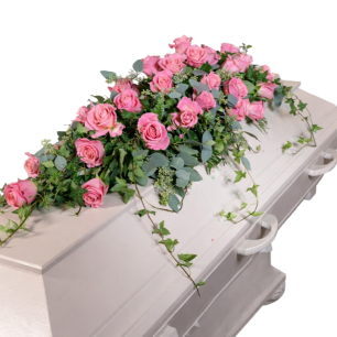 Vit kista dekorerad med ett arrangemang av rosa rosor och gröna blad.